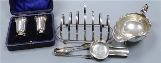 A silver sauceboat, a cased pair of silver condiments, a silver toastrack and three other silver items.